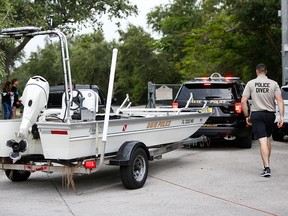 Police divers haul a boat to the entrance of Silver Lakes Rotary Nature Park, Friday, June 8, 2018, in Davie, Fla.