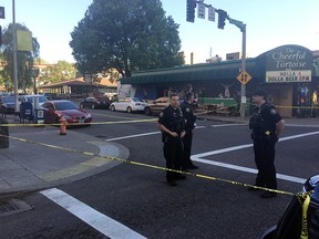 Police stand outside across from the Cheerful Tortoise bar at the scene of an earlier shooting in Portland, Ore., Friday, June 29, 2018. (Shane Dixon/The Oregonian via AP)