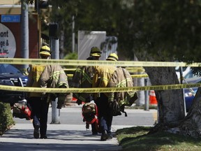 Long Beach firefighters walk along a street near a retirement home where at least one firefighter was killed in Long Beach, Calif., on Monday, June 25, 2018. A resident of the retirement home in Southern California opened fire on firefighters responding to a report of an explosion in the building, officials said.
