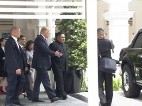 In this image made from video provided by Host Broadcaster Mediacorp Pte Ltd, U.S. President Donald Trump shows North Korean leader Kim Jong Un, center, his presidential vehicle outside the Capella Hotel in Singapore, Tuesday, June 12, 2018. (Host Broadcaster Mediacorp Pte Ltd via AP)