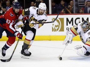 Washington Capitals forward Jay Beagle, left, checks Vegas Golden Knights defenseman Shea Theodore, center as Golden Knights goaltender Marc-Andre Fleury tries to control the puck, right, during the second period in Game 3 of the NHL hockey Stanley Cup Final, Saturday, June 2, 2018, in Washington.