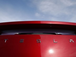 In this April 15, 2018, file photo the sun shines off the rear deck of a roadster on a Tesla dealer's lot in the south Denver suburb of Littleton, Colo.