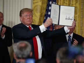 U.S. President Donald Trump shows off a "Space Policy Directive" after signing it during a meeting of the National Space Council in the East Room of the White House, Monday, June 18, 2018, in Washington.