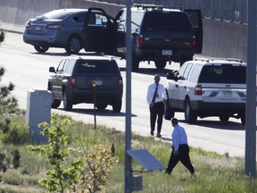 Denver Police Department detectives, foreground, investigate near where a Nissan sedan, top left, being driven by an Uber driver crashed into a retaining wall along Interstate 25 south of downtown Denver early Friday, June 1, 2018. The driver allegedly shot and killed a passenger at 2:45 a.m. after a confrontation broke out between the two while headed southbound on the interstate. (AP Photo/David Zalubowski)