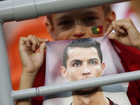 A young boy wears a shirt with a picture of Portugal's Cristiano Ronaldo on it as he waits for the start of the Iran-Portugal match at the 2018 World Cup at the Mordovia Arena in Saransk, Russia, Monday, June 25, 2018.