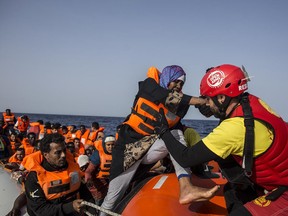 A migrant aboard a rubber dinghy off the Libyan coast is helped by rescuers aboard the Open Arms aid boat, of Proactiva Open Arms Spanish NGO, Saturday, June 30, 2018. 60 migrants were rescued as Italy's right-wing Interior Minister Matteo Salvini tweeted: "They can forget about arriving in an Italian port."