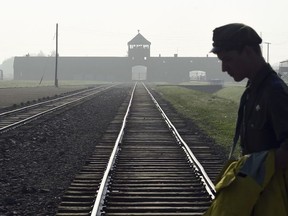 FILE - In this July 29, 2016 file photo a man crosses the iconic rails leading to the former Nazi death camp of Auschwitz-Birkenau prior to a visit by Pope Francis, in Poland.
