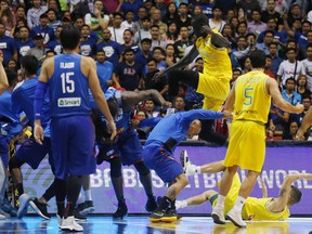 The Philippines players, left and Australian basketball players react, during the FIBA World Cup Qualifiers Monday, July 2, 2018 at the Philippine Arena in suburban Bocaue township, Bulacan province north of Manila, Philippines. Australia defeated the Philippines 89-53 via default following a brawl in the third quarter. (AP Photo/Bullit Marquez)