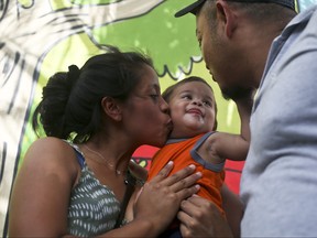 Adalicia Montecino kisses her year-old son Johan Bueso Montecinos, who became a poster child for the U.S. policy of separating immigrants and their children, as Johan touches his father Rolando Bueso Castillo's face, in San Pedro Sula, Honduras, Friday, 20, 2018. (AP Photo/Esteban Felix)