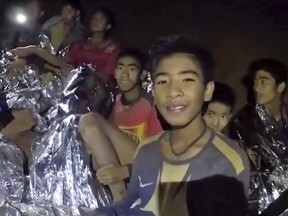 In this July 3, 2018, file image taken from video provided by the Royal Thai Navy Facebook Page, the boys smile as Thai Navy SEAL medic help injured children inside a cave in Mae Sai, northern Thailand. (Royal Thai Navy Facebook Page via AP, File)