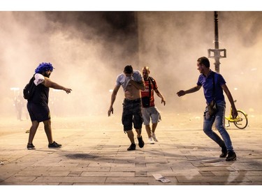 PARIS, FRANCE - JULY 15: People run from tear gas as French football fans clash with police following celebrations around the Arc de Triomph after France's victory against Croatia in the World Cup Final on July 15, 2018 in Paris, France. France beat Croatia 4-2 in the World Cup Final played at Moscow's Luzhniki Stadium today.
