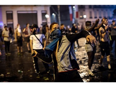 PARIS, FRANCE - JULY 15: A man throws a stone as French football fans clash with police following celebrations around the Arc de Triomph after France's victory against Croatia in the World Cup Final on July 15, 2018 in Paris, France. France beat Croatia 4-2 in the World Cup Final played at Moscow's Luzhniki Stadium today.