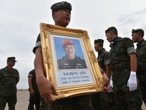 A Royal Thai Navy soldier carries a portrait of Saman Gunan, a former navy SEAL who died in an accident in Tham Luang cave in a rescue mission for the trapped 12 boys and their coach during arrival honors for Gunan's remains at a military base in Chon Buri province  on July 6, 2018. (PANUMAS SANGUANWONG/AFP/Getty Images)