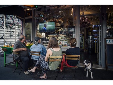 TOPSHOT - People sit in a grocery's shop on July 15, 2018 to watch the Russia 2018 World Cup final football match between France and Croatia, in Paris.