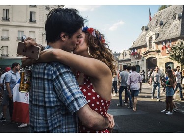 TOPSHOT - A couple kiss as they celebrate after France won the Russia 2018 World Cup final football match between France and Croatia, outside the "Le Carillon" bar in Paris on July 15, 2018, where the attacks of November 2015 took place.
