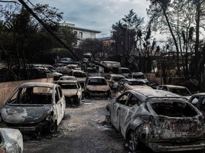 TOPSHOT - This photo taken on July 24, 2018 show cars burnt following a wildfire at the village of Mati, near Athens, on July 24, 2018. Fifty people have died and 170 have been injured in wildfires ravaging woodland and villages in the Athens region, as Greek authorities rush to evacuate residents and tourists stranded on beaches along the coast on July 24, 2018. The death toll soared with a Red Cross official reporting the discovery of 26 bodies in the courtyard of a villa at the seaside resort of Mati.