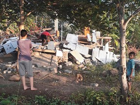 This handout photograph taken on July 29, 2018 and released by the Nusa Tenggara Barat Disaster Mitigation Agency (BPBD) show an Indonesian person scrambling over the collapsed ruins of a house as others look on following an earthquake in Lombok. (AFP PHOTO/Nusa Tenggara Barat Disaster Mitigation Agency)