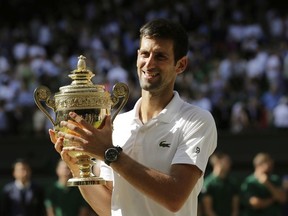 Novak Djokovic of Serbia holds the trophy after defeating Kevin Anderson of South Africa in the men's singles final match at the Wimbledon Tennis Championships in London, Sunday July 15, 2018.