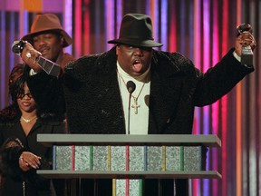 In this Dec. 6, 1995, file photo, The Notorious B.I.G., who won rap artist and rap single of the year, clutches his awards at the podium during the annual Billboard Music Awards in New York.