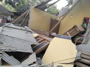 In this image made from video released by Indonesia's Disaster Mitigation Agency, a man inspects the damage caused by an early morning earthquake on the island of Lombok, Indonesia, Sunday, July 29, 2018. (Indonesia's Disaster Mitigation Agency via AP)