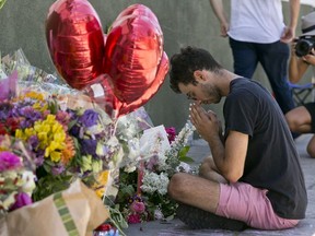 Paolo Singer, 27, a Silver Lake resident, prays at a makeshift memorial of flowers, candles and notes growing on the sidewalk outside the Silver Lake Trader Joe's store in Los Angeles, Monday, July 23, 2018.