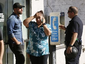 An unidentified Trader Joe's supermarket employee, centre, talks on her phone as Los Angeles Police evacuate a group of witnesses after a gunman barricaded himself inside the store in Los Angeles, Saturday, July 21, 2018.