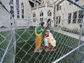 This Tuesday, July 3, 2018 photo shows statues of Mary, Joseph and the baby Jesus in a cage of fencing topped with barbed wired on the lawn of Monument Circle's Christ Church Cathedral in Indianapolis.  The statues were erected  to protest the Trump administration's zero tolerance immigration policy.