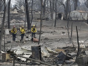 San Bernardino County Fire department firefighters assess the damage to a neighborhood in the aftermath of a wildfire, Sunday, July 29, 2018, in Keswick, Calif. (AP Photo/Marcio Jose Sanchez)