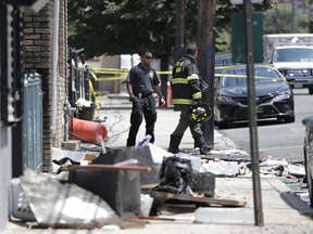 Fire officials stand outside of a house where two children were killed in a morning fire, Friday, July 13, 2018, in Union City, N.J. (AP Photo/Julio Cortez)