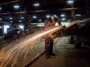 Fabricator Mike Caldarino uses a grinder on a steel stairs being manufactured for a high school in Redmond, Wash., at George Third & Son Steel Fabricators and Erectors, in Burnaby, B.C., on March 29, 2018. (THE CANADIAN PRESS/Darryl Dyck)