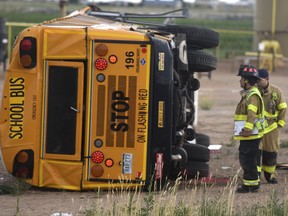 Firefighters gather around a school bus that flipped near the intersection of Weld County Road 49 and Weld County Road 24 near Hudson, Colo., Thursday, July 12, 2018. (Joshua Polson/The Greeley Tribune via AP)