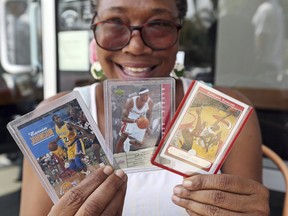 Janice Evans, of Los Angeles, displays her collector cards of LeBron James and Earvin "Magic" Johnson as she waits in line around noon for promised free pizza that will be handed out between 2 and 5 p.m. at Blaze Pizza, a restaurant chain NBA basketball player LeBron James was an original investor in, in Culver City, Calif., Tuesday, July 10, 2018. (AP Photo/Reed Saxon)