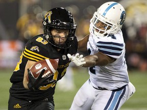 Hamilton Tiger-Cats receiver Andy Fantuz (83) makes a one-handed catch while defended by Toronto Argonauts defensive back Brandon Harris (4) during CFL action in Hamilton on Saturday, September 30, 2017. (THE CANADIAN PRESS/Peter Power)