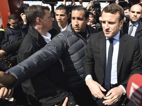In this Wednesday April 26, 2017 file photo Emmanuel Macron, flanked by bodyguard Alexandre Benalla, left, arrives outside the Whirlpool home appliance factory, in Amiens, northern France.