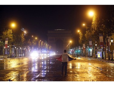 A man wearing his French national flag stand in the middle of the Champs Elysees avenue as police starts to evacuate the avenue after clashes broke out as soccer fans were celebrating France's World Cup victory over Croatia in Paris, France , Sunday, July 15, 2018 in Paris. France won its second World Cup title by beating Croatia 4-2.