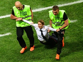 A pitch invader, a member of the Russian protest-art group Pussy Riot, is escorted by stewards during the Russia 2018 World Cup final football match between France and Croatia at the Luzhniki Stadium in Moscow on July 15, 2018. (Mladen Antonov/Getty Images)