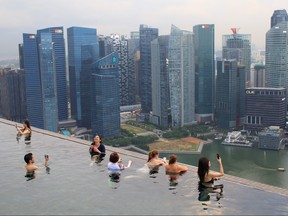 People using their phones to take photos in the rooftop pool of the Marina Bay Sands resort hotel, which overlooks the financial district skyline of Singapore, on June 13, 2018. (Anthony Wallace/Getty Images)