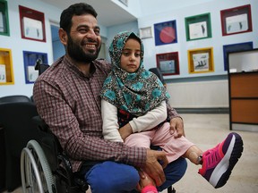 In this Thursday, July 5, 2018 photo, Maya Meri sits on her father Mohammed's lap after being fitted with prosthetic legs at a rehabilitation clinic in Istanbul. (AP Photo/Lefteris Pitarakis)