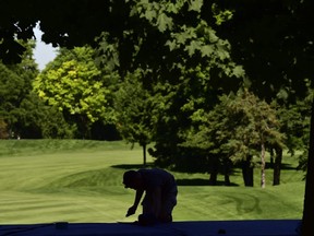 A worker puts the final touches on carpeting at the 16th green viewing area at Glen Abbey golf course in Oakville, Ont., on Tuesday, July 3, 2018. THE CANADIAN PRESS/Frank Gunn