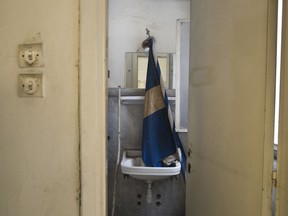 In this Tuesday, June 12, 2018 photo, a Greek flag in a washbasin inside a 7-story block off central Athens' gritty Omonia Square, that has been untenanted since a now-defunct farm cooperative fund left years ago. (AP Photo/Petros Giannakouris)