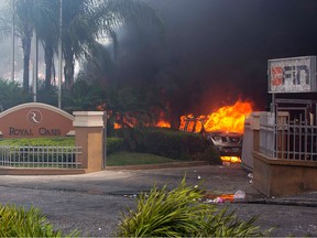 Cars burn outside the Royal Oasis hotel during protests over a fuel price increase in Port-au-Prince, Haiti, on Saturday, July 7, 2018.