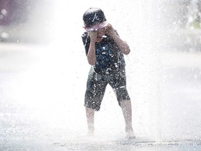 Seven-year-old Samuel Bedard from Quebec City runs through a water fountain as he beats the heat in Montreal, Monday, July 2, 2018. (THE CANADIAN PRESS/Graham Hughes)