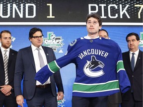 Defenceman Quinn Hughes dons a Vancouver Canucks jersey after the Canucks selected him during the NHL hockey draft in Dallas, Texas, Friday, June 22, 2018. (THE CANADIAN PRESS/AP-Michael Ainsworth)