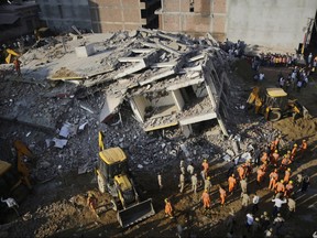 Rescuers work at the site of a building that collapsed in Shahberi village, east of New Delhi, India, Wednesday, July 18, 2018.