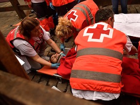 A reveller is taken in a stretcher after being injured during the running of the bulls at the San Fermin Festival, in Pamplona, northern Spain, Friday, July 13, 2018.