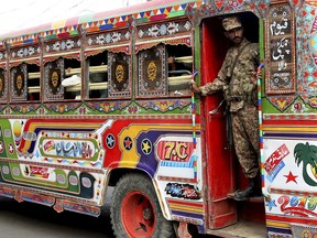 A Pakistani soldier stands guard in a bus carrying election staff and polling related material to stations in Karachi, Pakistan, Tuesday, July 24, 2018. (AP Photo/Shakil Adil)