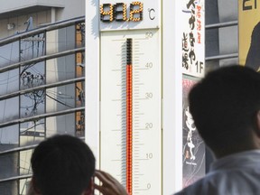 People watch the thermometer which reads 41.2 degree Celsius near Tajimi station, Gifu prefecture, central Japan, on July 18, 2018. (AP Photo/Yoshiaki Sakamoto)