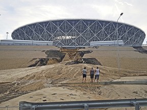 Three men look at a major landslide on an embankment after a heavy rain next to the Volgograd Arena, one of Russia's World Cup venues in Volgograd, Russia, Sunday, July 15, 2018. (AP Photo/Ilya Varlamov)