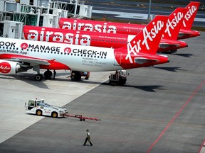 In this May 9, 2014 photo, a technical crew walks past a fleet of AirAsia's planes taxied on the tarmac of Kuala Lumpur International Airport 2 in Sepang.