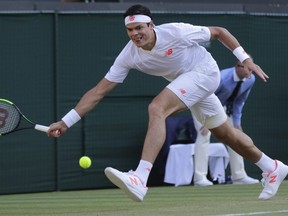 Milos Raonic returns the ball to John Isner during their men's quarterfinal match at Wimbledon, in London, Wednesday July 11, 2018.
